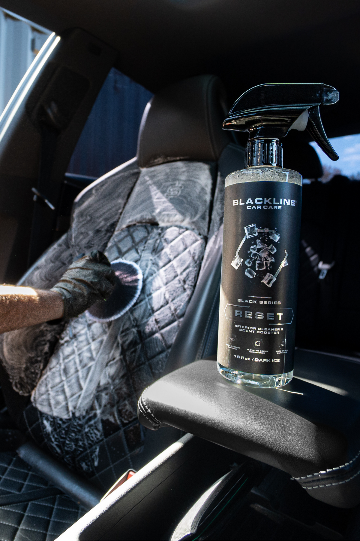 Hand spraying Blackline Reset scented interior cleaner on a leather car seat