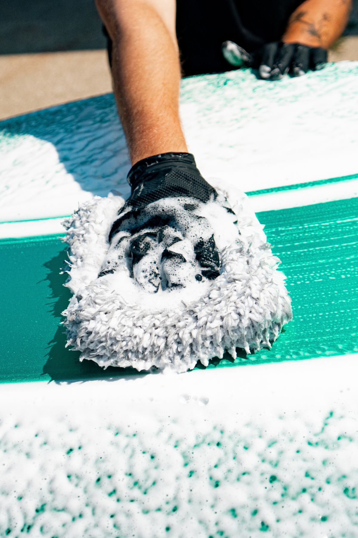 Blackline Shampoo suds covering a vehicle hood during exterior car washing.