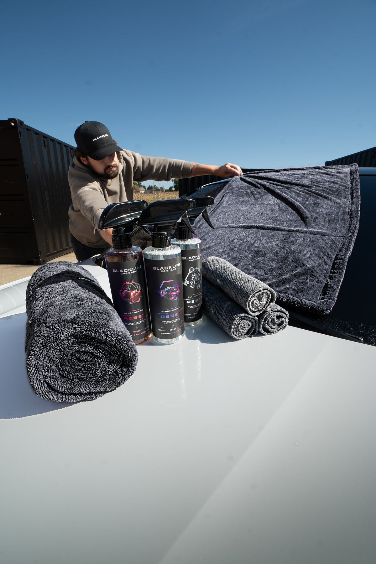 Lifestyle shot of Blackline drying towel drying a vehicle panel with zero streaks