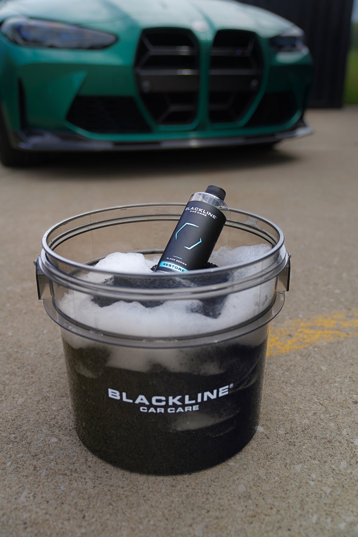 Blackline Restore Microfiber Detergent bottle and microfiber towels beside a wash bucket
