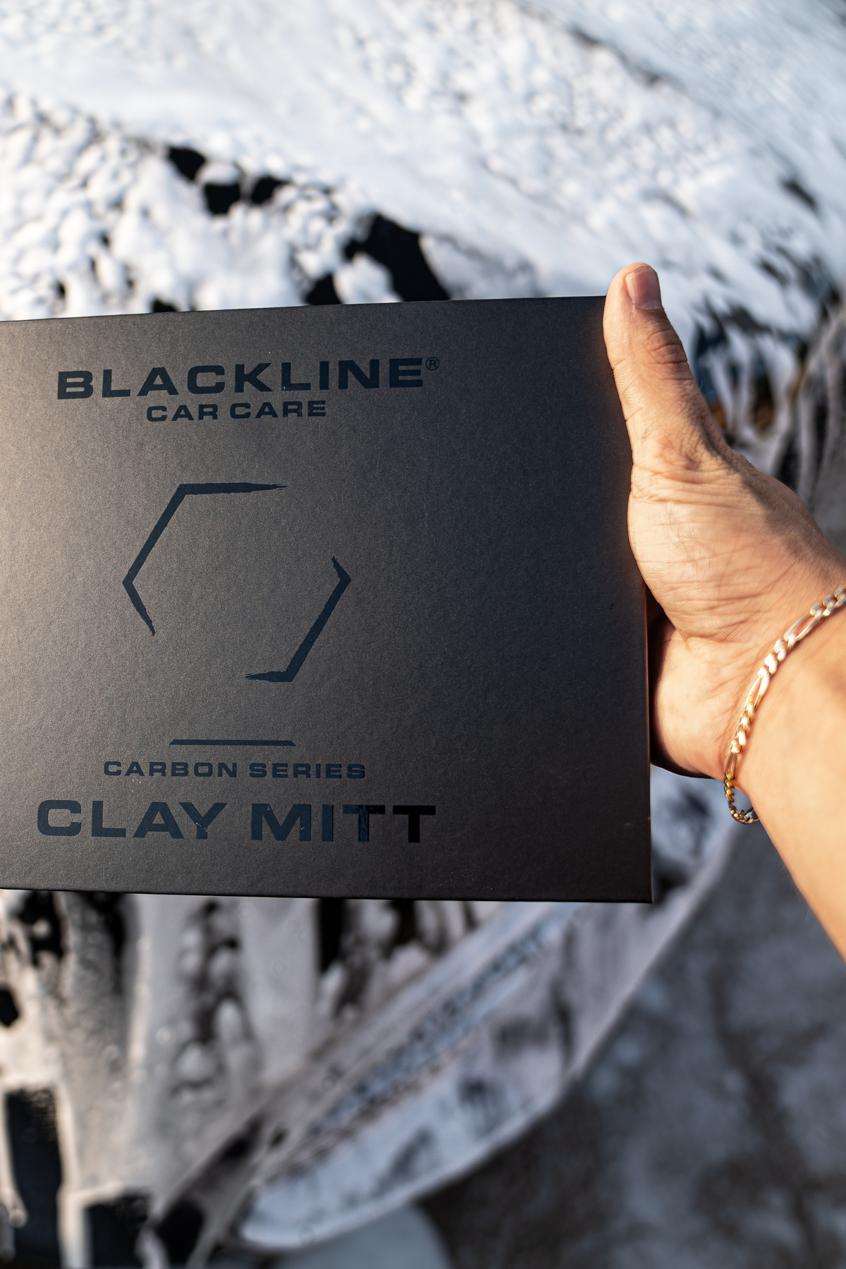 Blackline Clay Mitt being worked across a car's clear-coat to remove bonded contaminants.