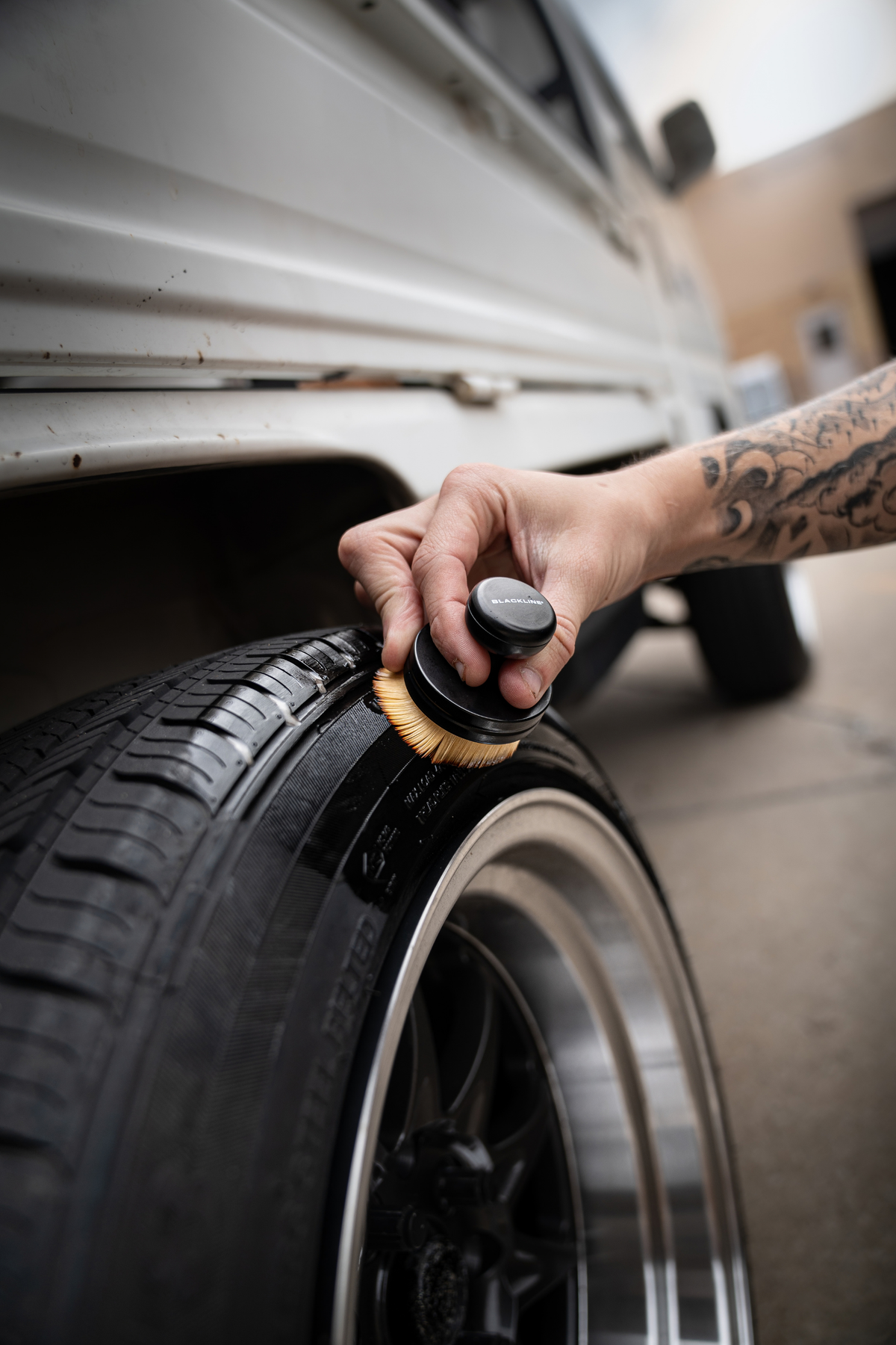 Hand gripping Blackline Tire Shine Applicator Brush handle during tire shine application