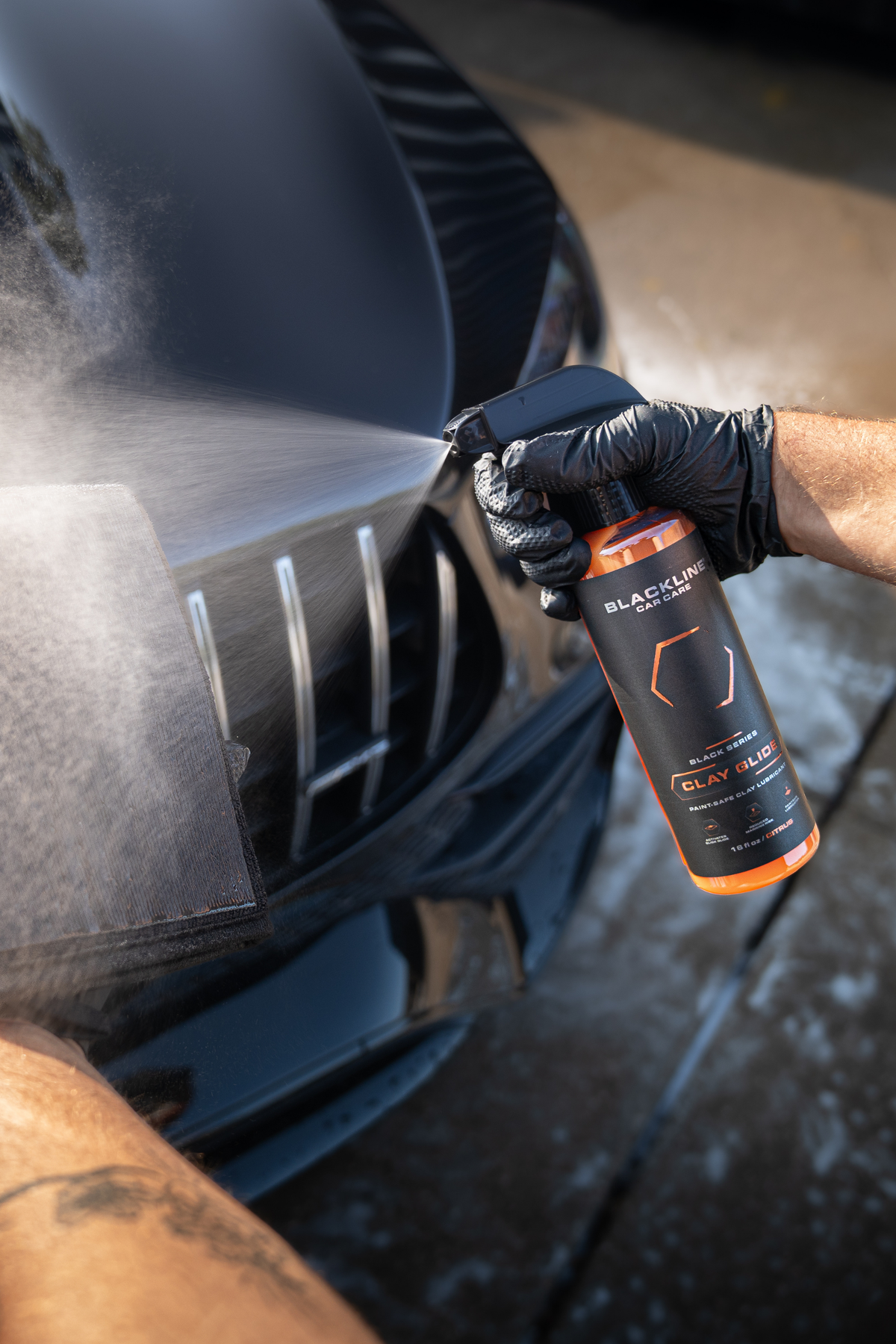 Blackline Clay Glide spray being applied to a car paint panel for clay decontamination