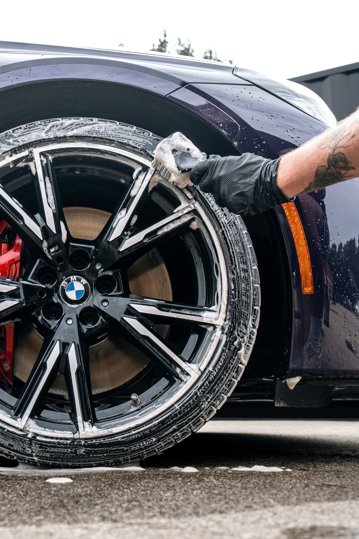 Hand scrubbing a brake-dust-covered wheel rim with Blackline Wheel and Tire solution.