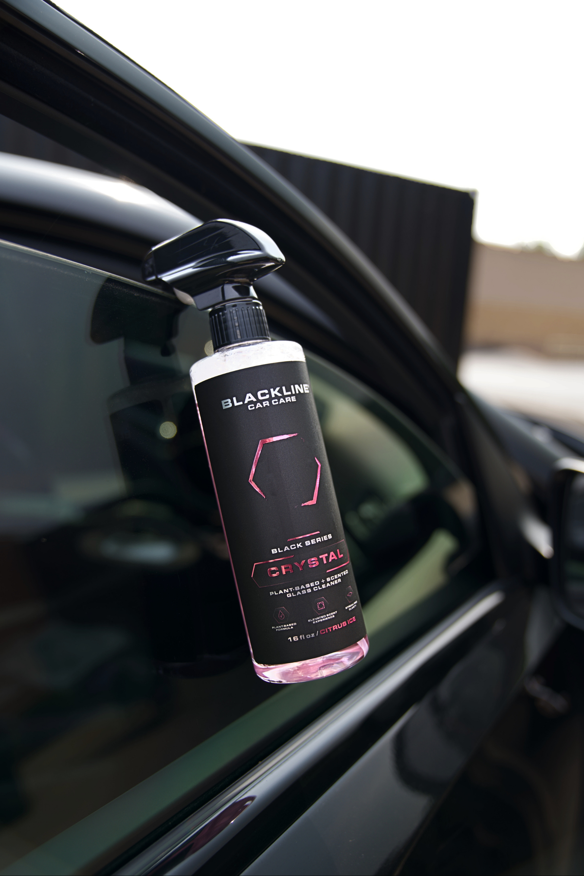 Blackline Crystal Glass Cleaner being sprayed on a glossy car exterior window