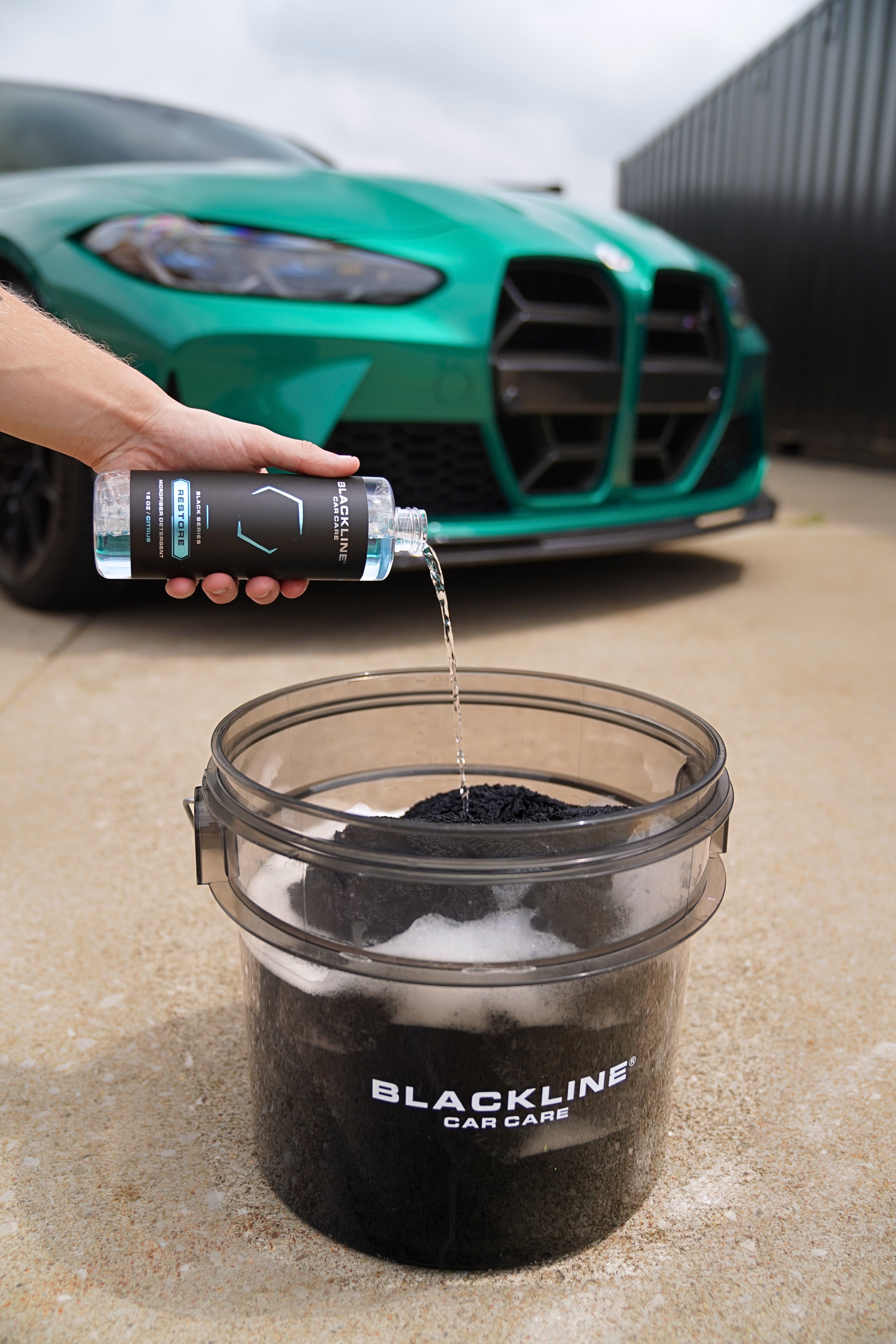 Blackline Restore Microfiber Detergent bottle next to a detailing wash bucket