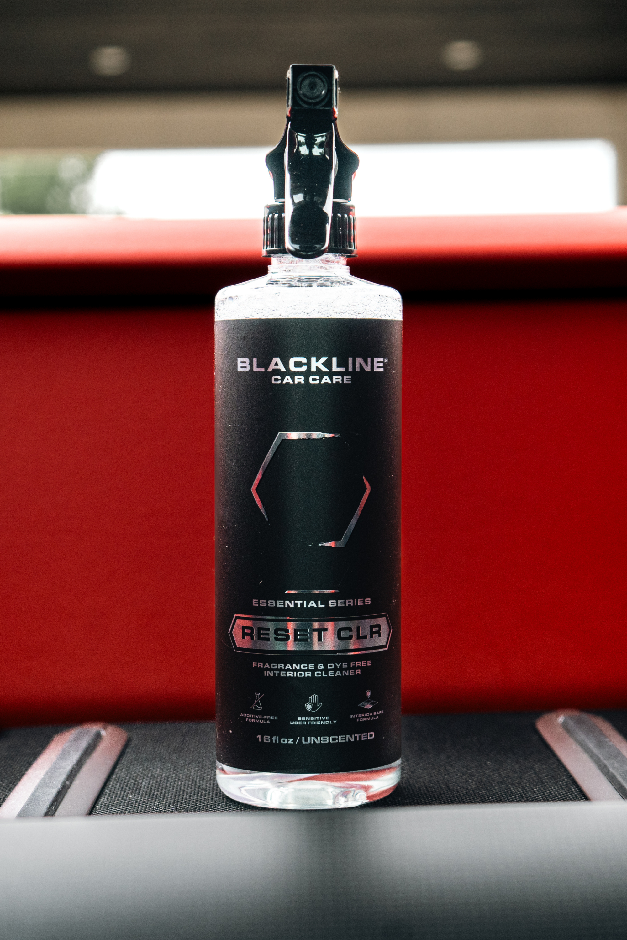 Blackline Reset interior cleaner bottle sitting in a red car interior
